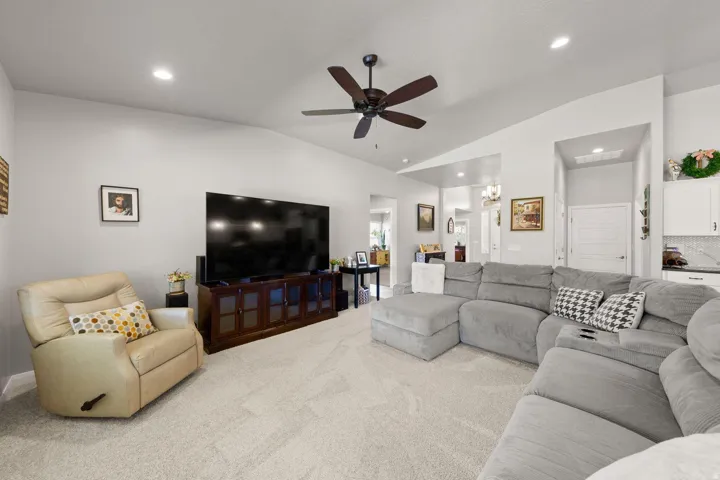 Spacious living area featuring vaulted ceilings, recessed lighting, and a ceiling fan