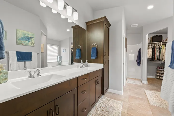 Bathroom vanity featuring dual undermount sinks, chrome fixtures, and a white countertop