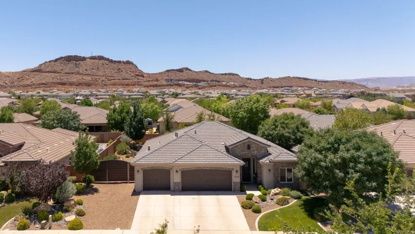 Single-story residence featuring a two-car garage, stone and stucco exterior, and a tiled roof