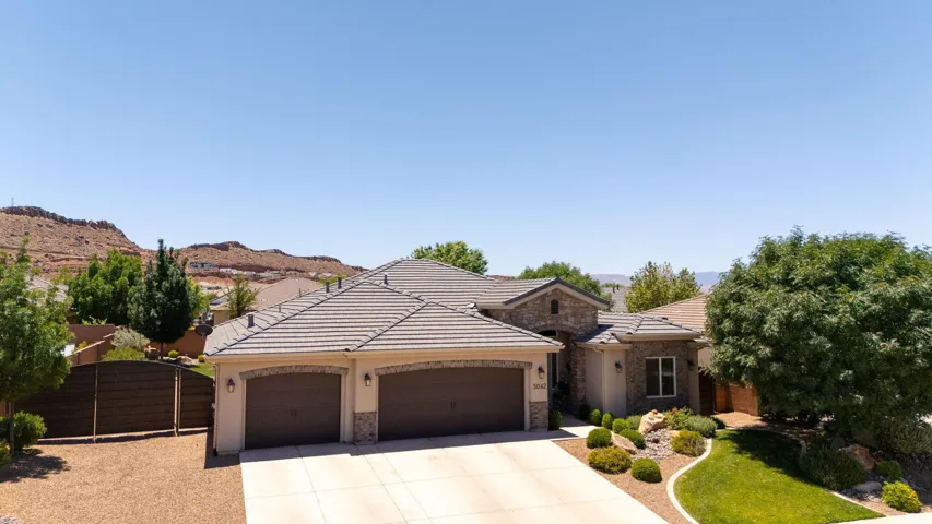 Stately residence featuring a stone and stucco facade, a tile roof, and a two-car garage