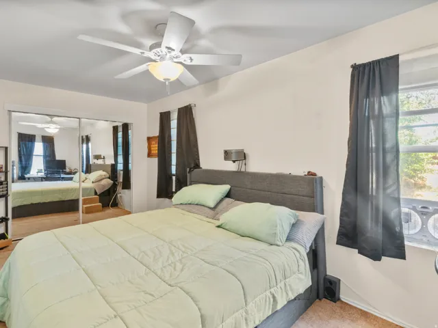 Ceiling fan with integrated lighting, mirrored closet doors, and wall-mounted light fixture