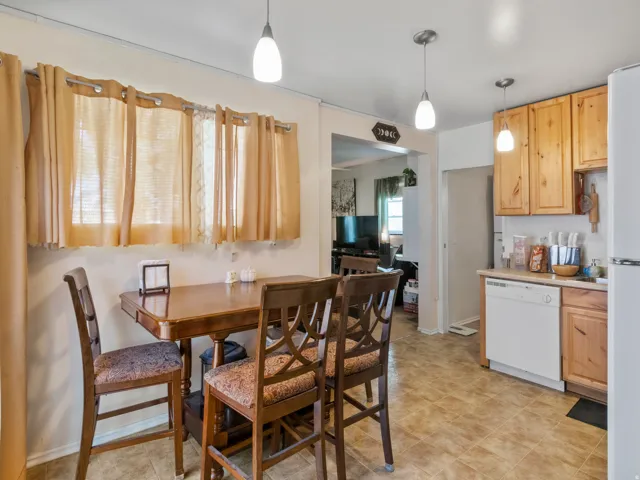 Kitchen area with wood-finish cabinetry, white dishwasher, and pendant lighting fixtures