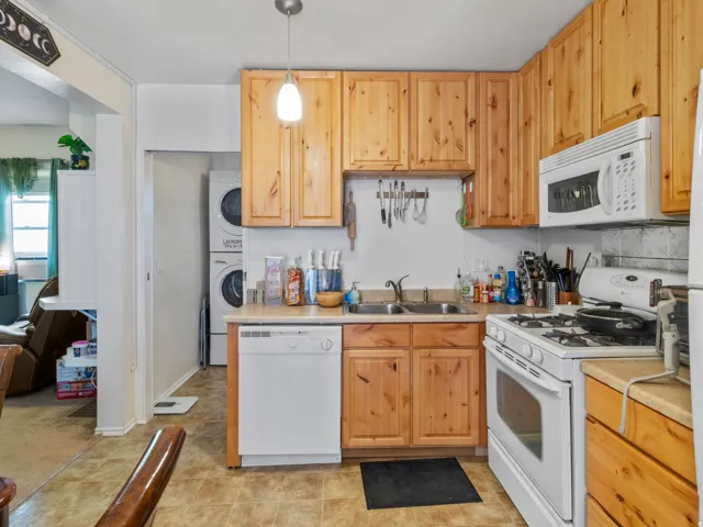 Kitchen featuring wood cabinetry, laminate countertops, a double basin sink, and a white appliance suite including a dishwasher, range, and microwave