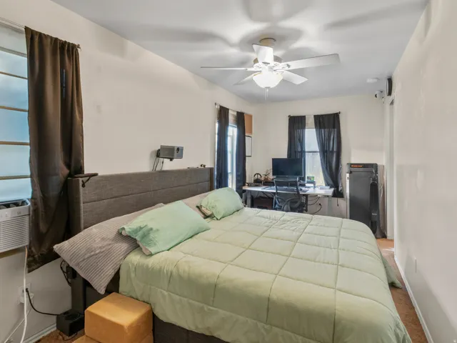 Bedroom featuring multiple windows, a ceiling fan with integrated lighting, and neutral wall tones