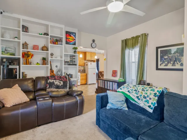 Living area featuring extensive built-in shelving, a ceiling fan with integrated lighting, and a window with natural light