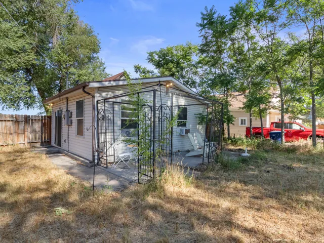 Rear exterior featuring white horizontal siding, a private patio area, a dark metal pergola, and a wooden fence boundary