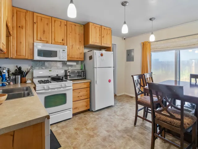 Kitchen and dining area featuring wood-finish cabinetry, a white gas range with an overhead microwave, and a double basin stainless steel sink