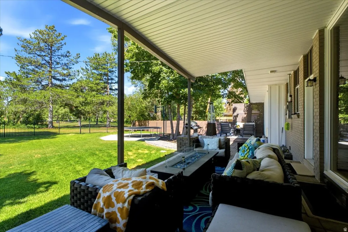 Covered patio area featuring a fire pit, outdoor seating, and brick exterior