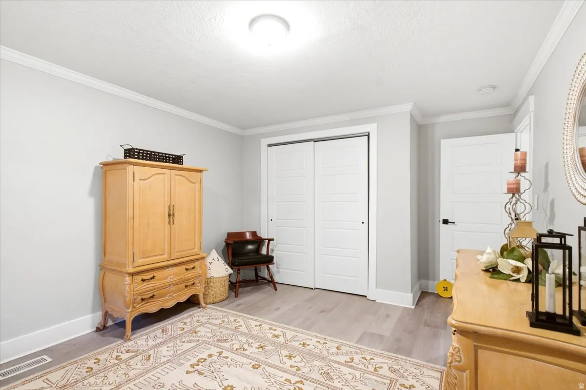 Interior room featuring light gray walls, white crown molding, and light wood-finish flooring