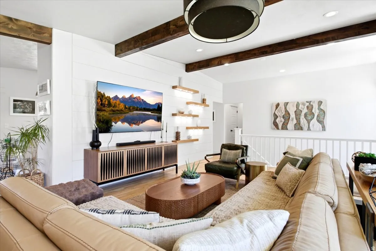 Spacious living area featuring exposed wood ceiling beams, white shiplap accent wall, and recessed lighting
