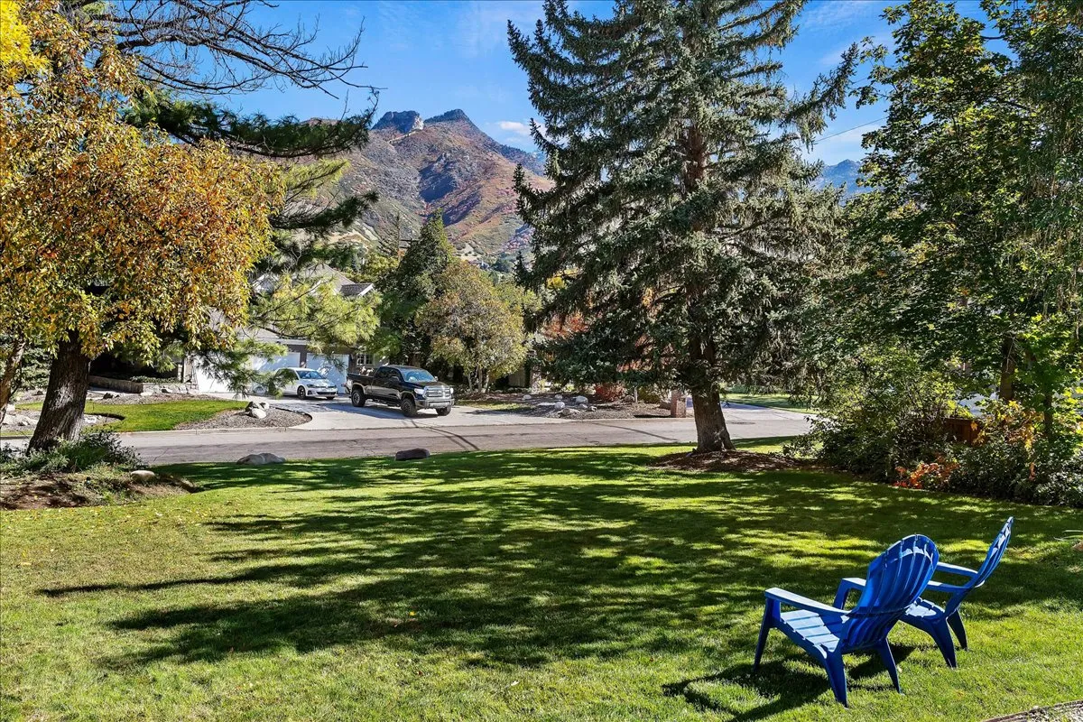Manicured lawn area with mature trees and mountain backdrop