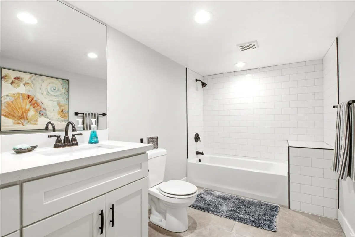 Bathroom featuring a white vanity with integrated sink, a rectangular wall-mounted mirror, and a toilet