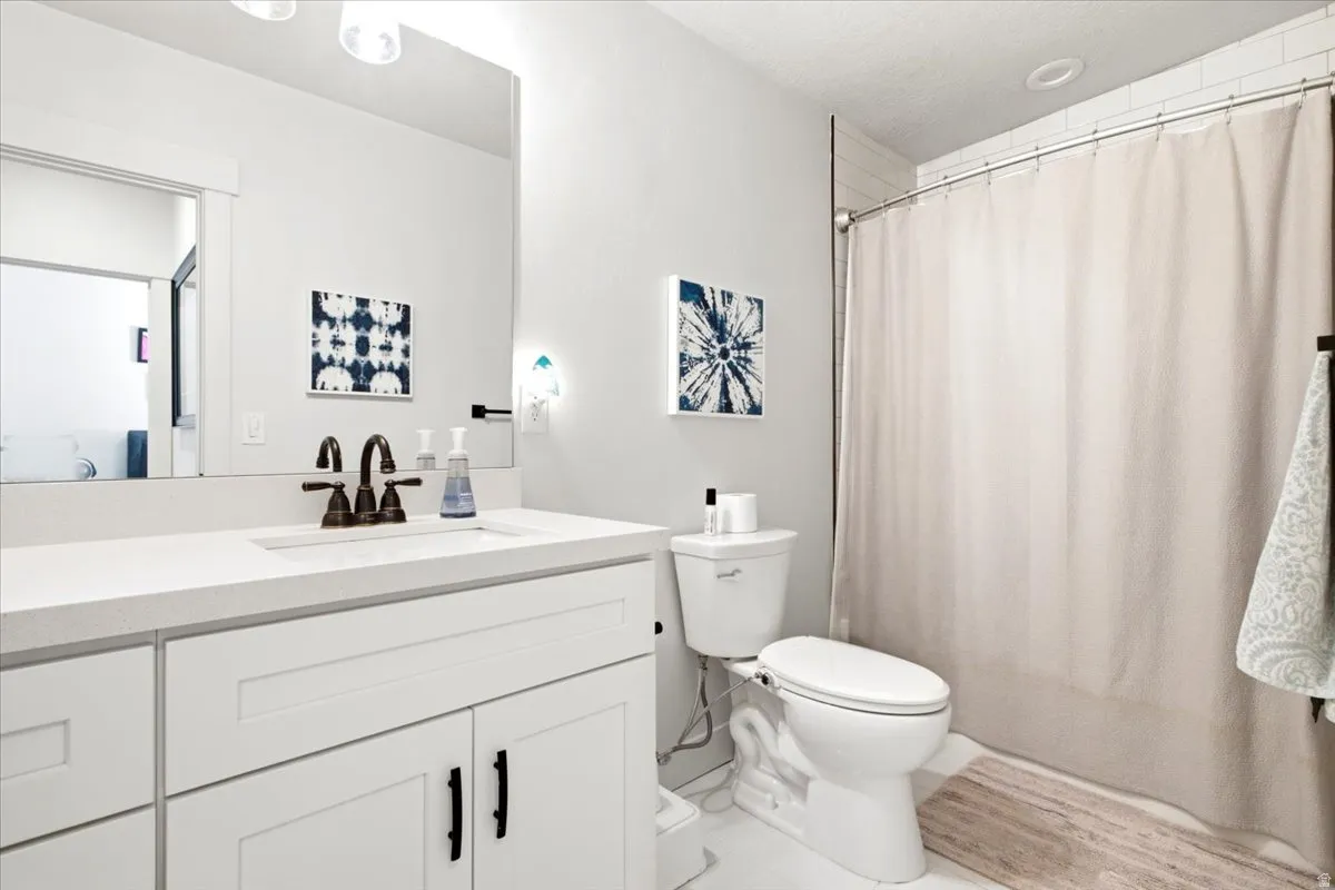 Bathroom featuring a white vanity with a quartz countertop, bronze-finish faucet, and a shower with white subway tile surround