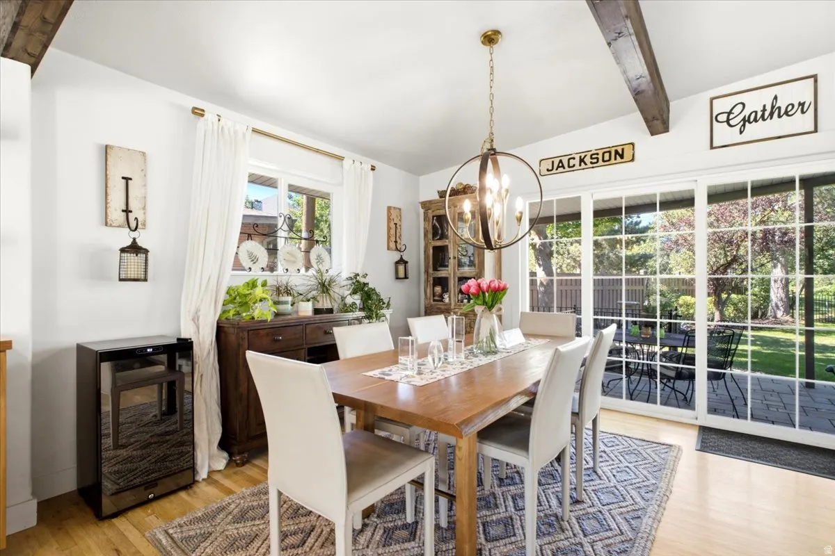 Dining area featuring wood-finish flooring, exposed ceiling beams, and a brass-finish chandelier