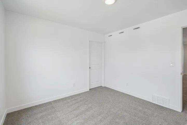 Neutral wall paint, gray carpet flooring, white trim, recessed lighting, and a paneled door