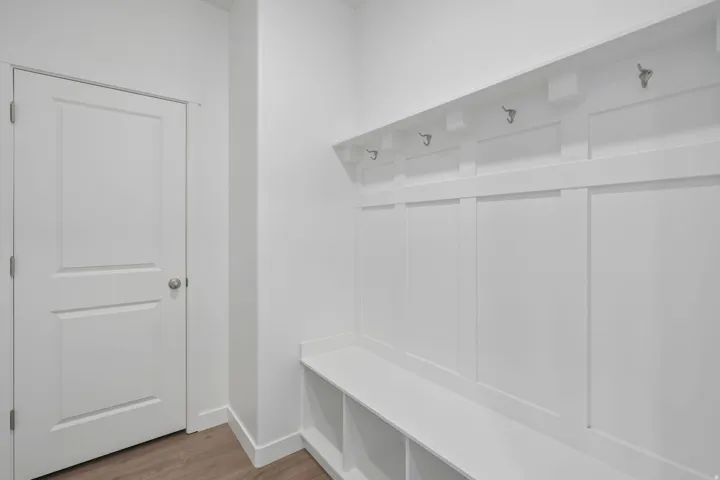 Built-in storage bench with open shelving, integrated wall hooks, and wood-finish flooring