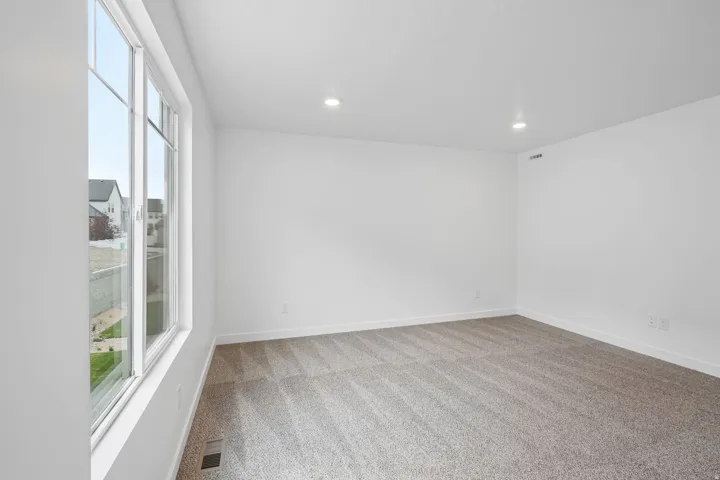 Bright room with large multi-pane windows, recessed ceiling lighting, and neutral carpeting