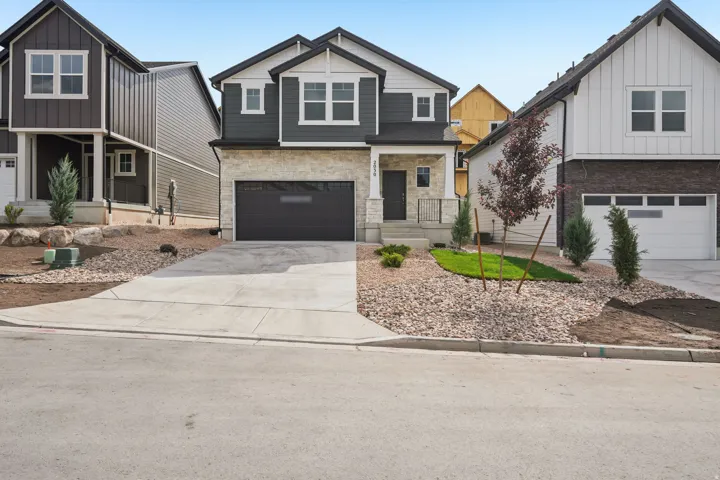 Contemporary two-story exterior with stone and horizontal siding accents, an attached two-car garage, and a concrete driveway