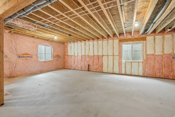 Unfinished lower level with wood beam ceiling, concrete flooring, and insulated walls