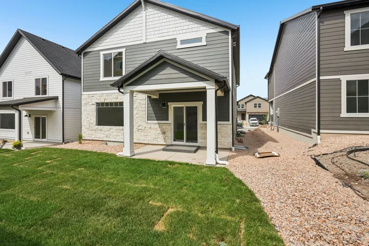 Modern exterior with grey horizontal siding, white trim, stone veneer accents, and a covered patio