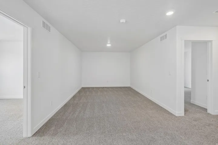 Recessed lighting throughout, neutral carpeting, and crisp white walls