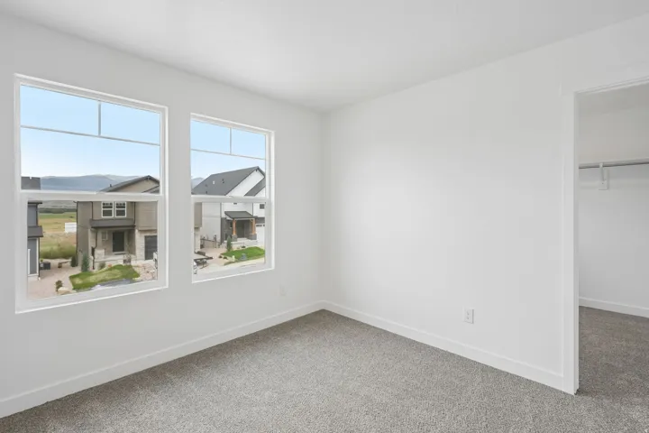 Wall-to-wall carpeting, dual windows with multi-pane inserts, white trim, and a built-in closet with shelving