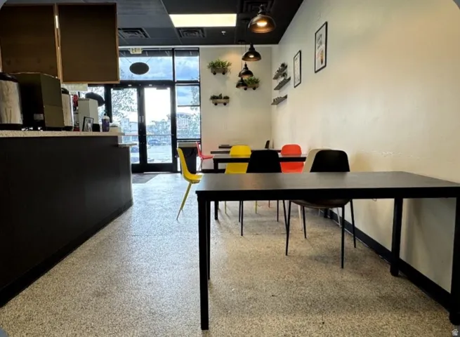 Spacious commercial interior featuring a full-glass storefront, terrazzo flooring, and a counter service area