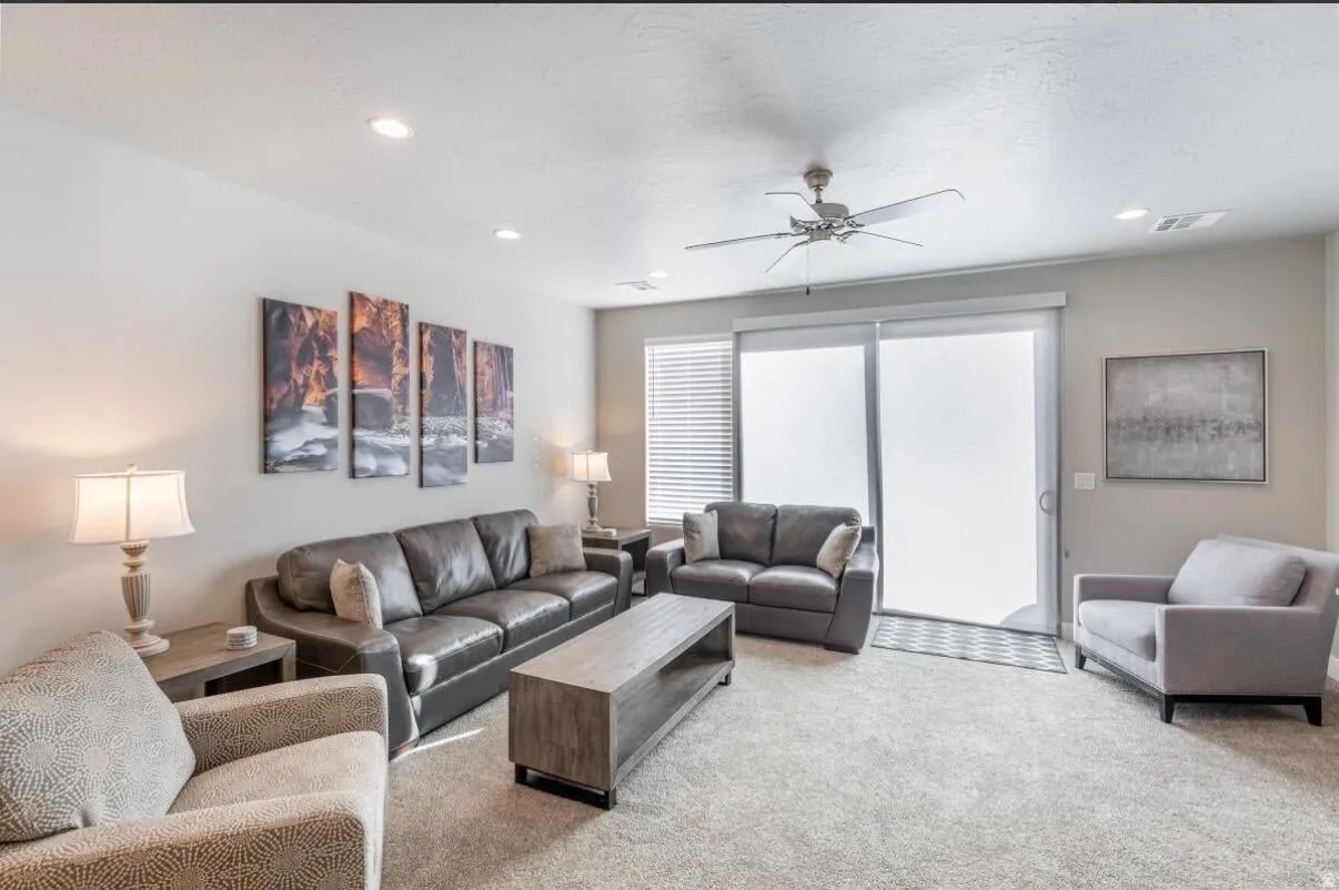 Spacious living area featuring soft carpet flooring, recessed lighting, and a ceiling fan