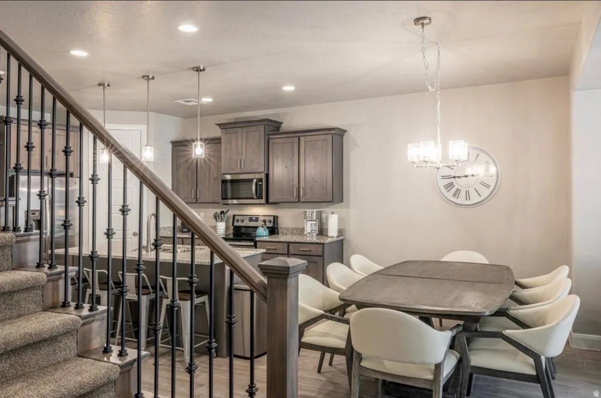 Open-concept kitchen and dining area featuring wood-finish flooring, recessed lighting, and a chandelier