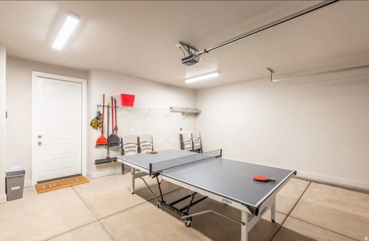 Spacious garage with concrete flooring, overhead fluorescent lighting, and a white interior door