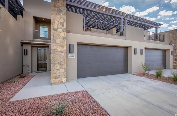 Contemporary stucco exterior featuring stacked stone accents and a textured wood-finish entry door