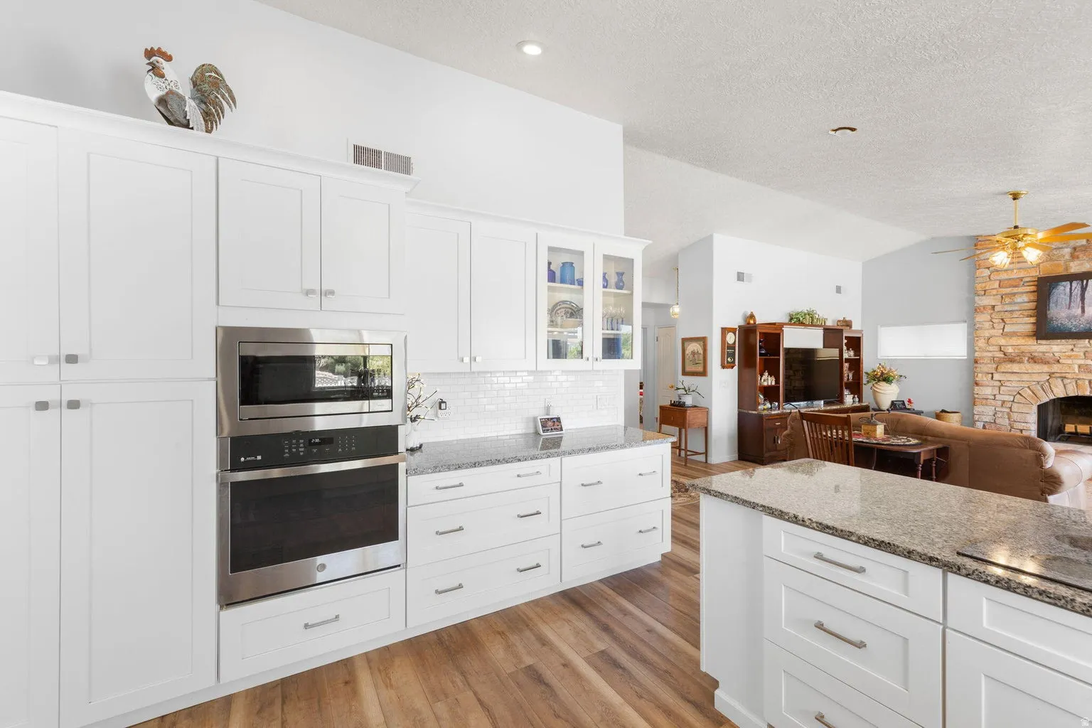 Bright kitchen featuring white shaker cabinetry and integrated stainless steel wall oven and microwave