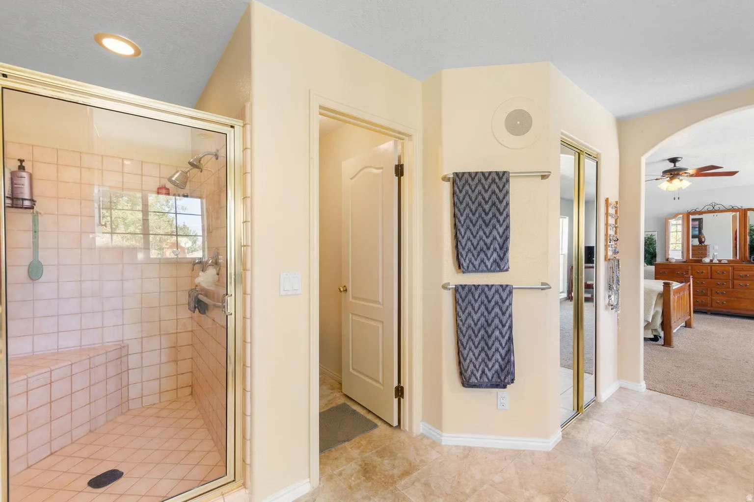 Glass-enclosed shower with tiled walls, integrated bench, and exterior window