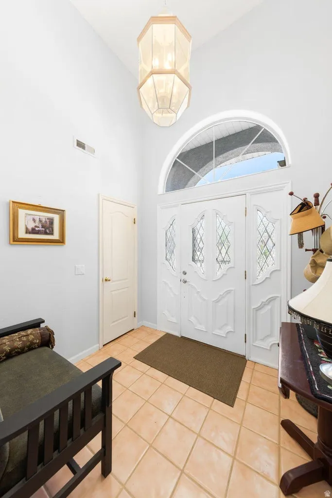 Entryway featuring a double door with decorative glass inserts, an arched transom window, and a high vaulted ceiling