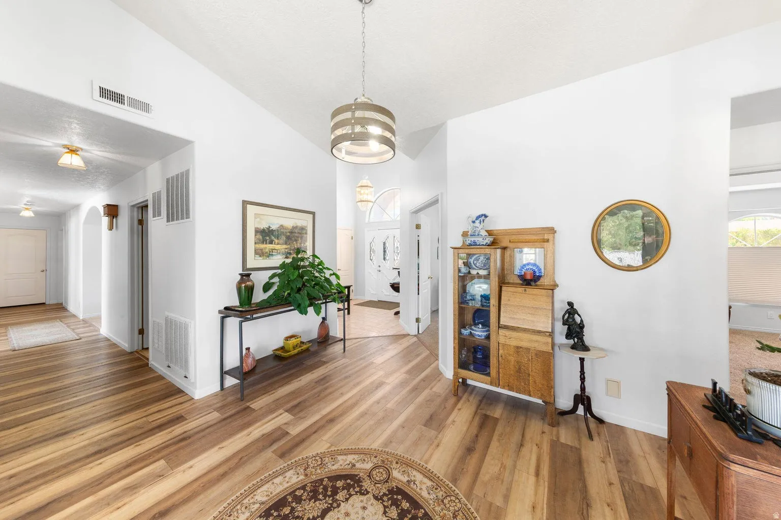 Entryway featuring vaulted ceilings, wood-finish flooring, a contemporary chandelier, and an arched doorway