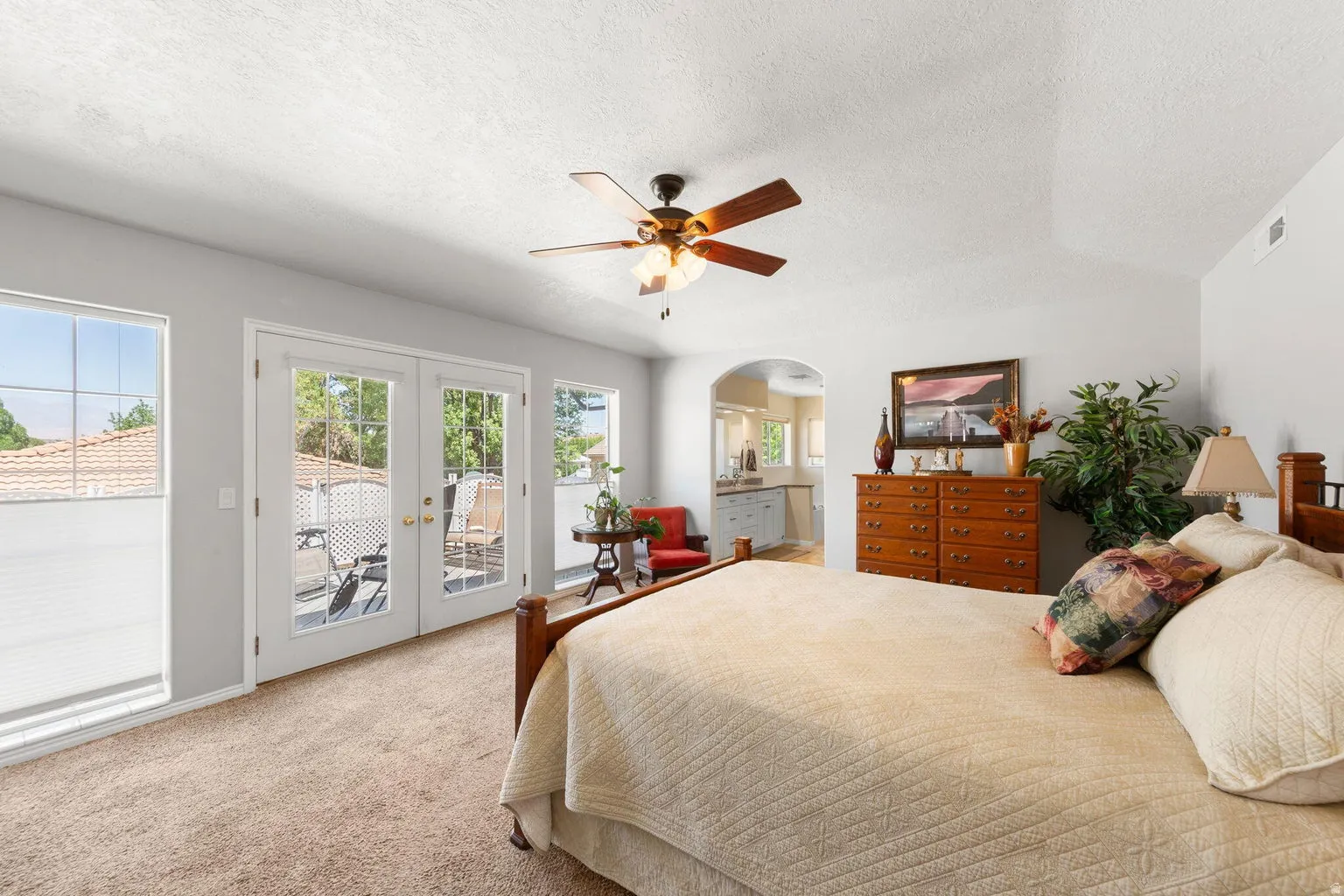 Carpeted room featuring a ceiling fan, vaulted ceiling, and dual pane glass paneled doors opening to an outdoor patio space