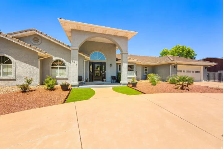 Stucco exterior featuring an arched portico entry with a transom window, arched windows, an attached two-car garage, and a concrete driveway