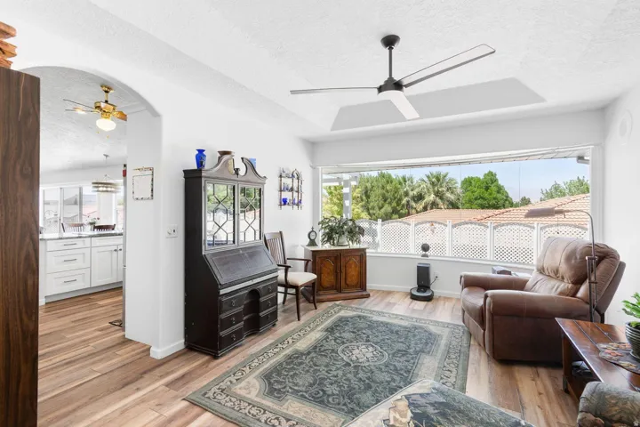 Living area featuring wood-finish flooring, a contemporary ceiling fan, and a wide window overlooking exterior landscaping