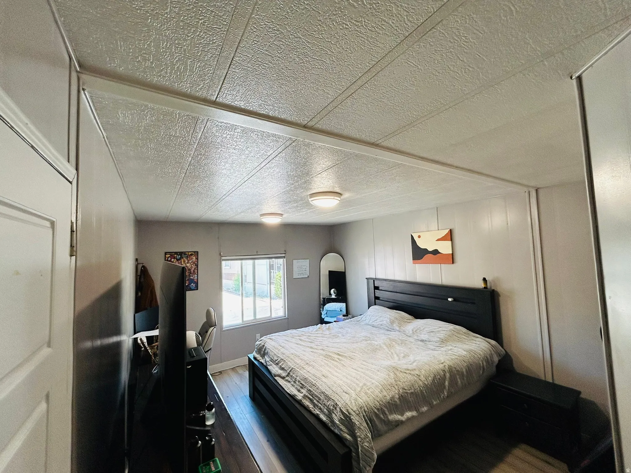 Bedroom featuring wood-finish flooring and light gray paneled walls