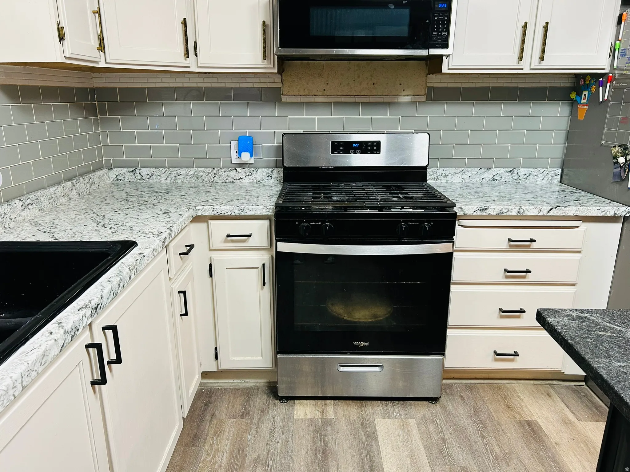 Stainless steel range with an overhead microwave, complemented by light-toned cabinetry and a subway tile backsplash