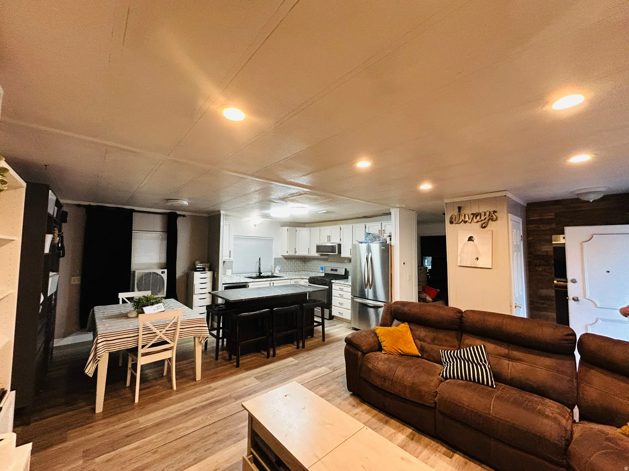 Open-concept living area with wood-finish flooring, recessed lighting, and a white interior door
