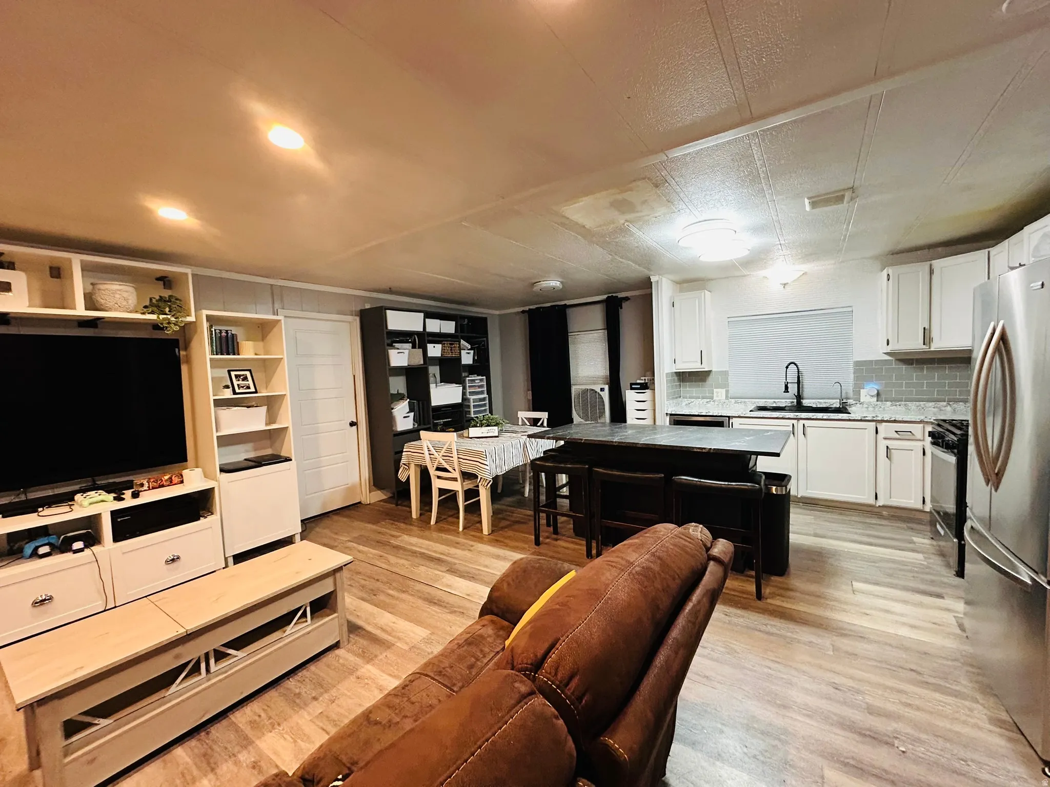 Open-concept living space featuring wood-finish flooring, recessed lighting, and a modern kitchen