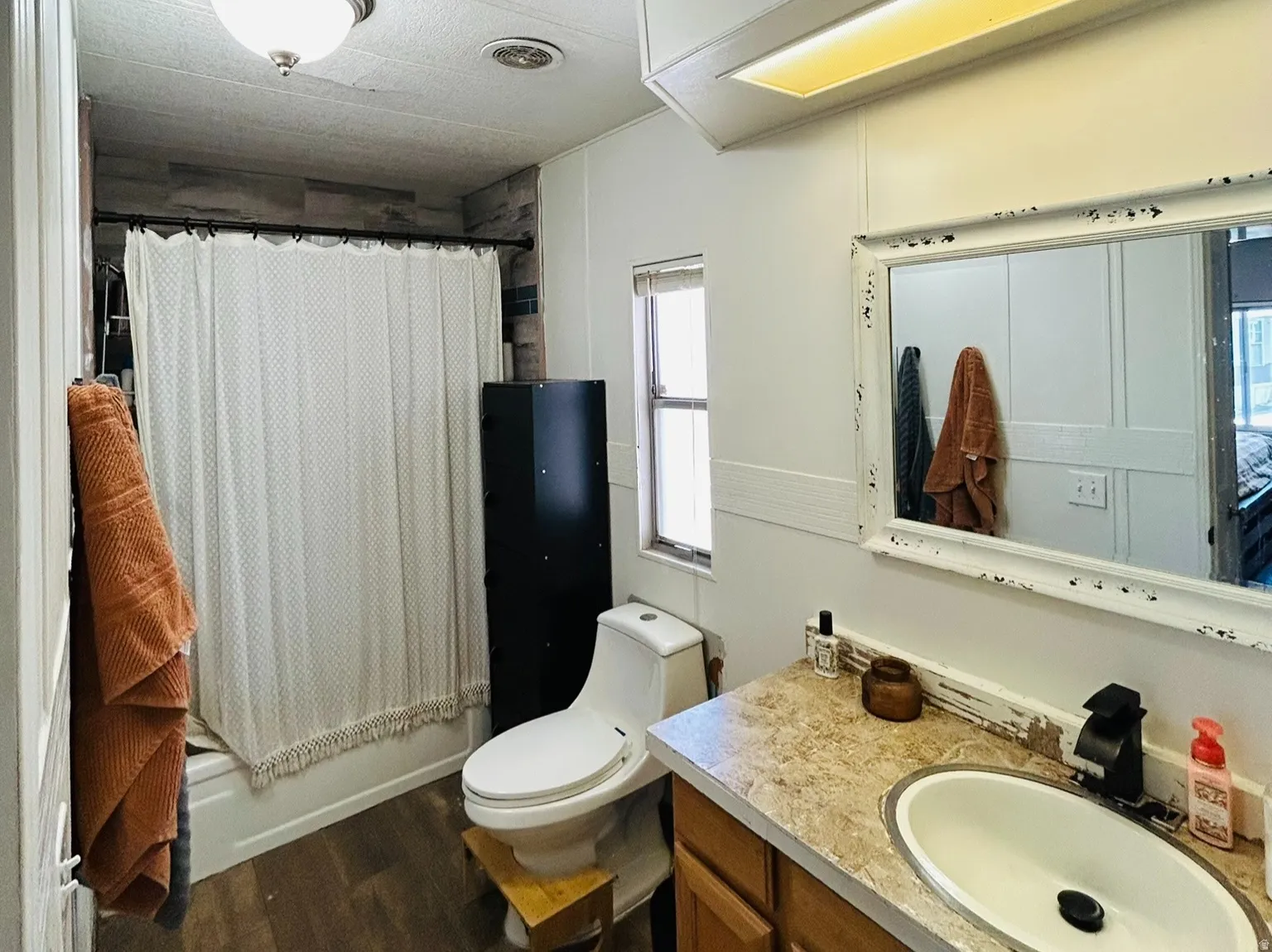 Bathroom featuring a vanity with wood-finish cabinetry, a single basin sink, and a framed mirror