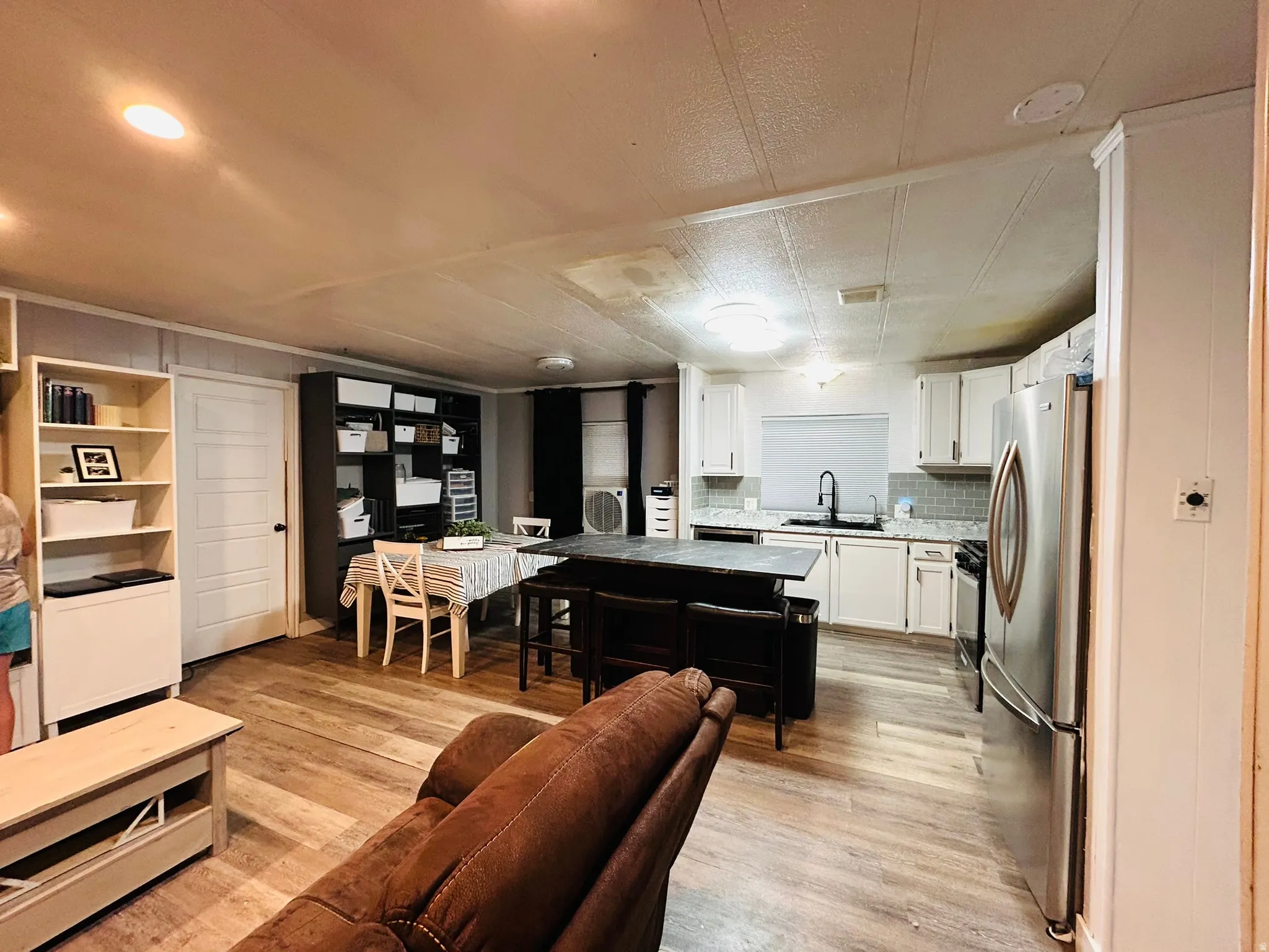 Open-concept kitchen and living area featuring wood-finish flooring, white cabinetry, and stainless steel appliances