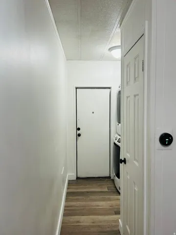 Hallway featuring wood-finish flooring, white paneled walls, and a recessed ceiling light
