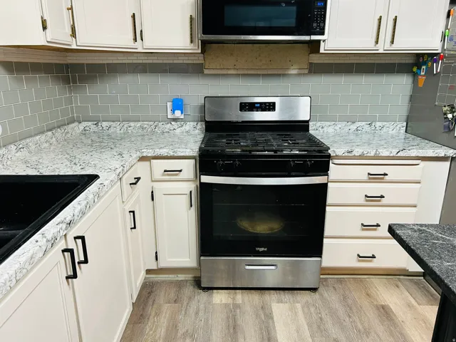 Stainless steel range with an overhead microwave, complemented by light-toned cabinetry and a subway tile backsplash