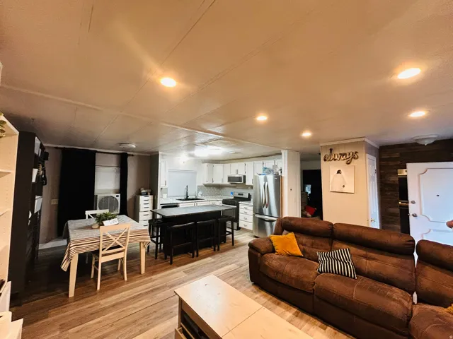 Open-concept living area with wood-finish flooring, recessed lighting, and a white interior door