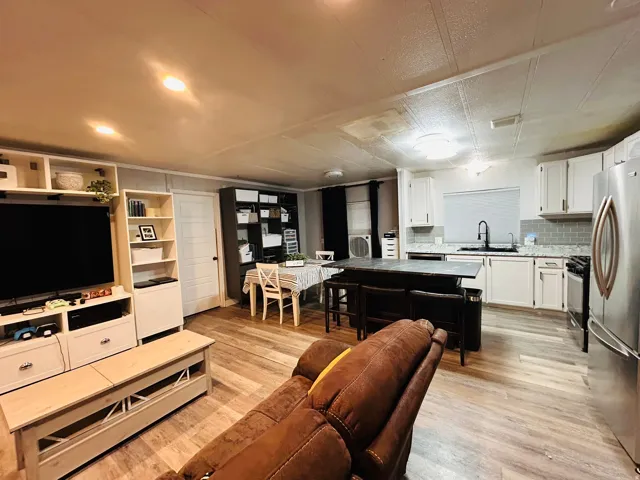 Open-concept living space featuring wood-finish flooring, recessed lighting, and a modern kitchen