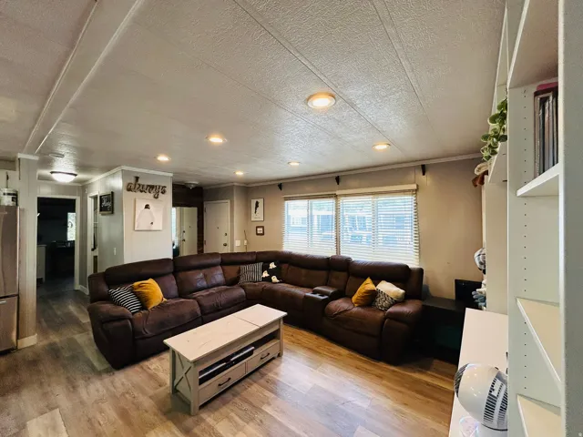 Open living area featuring wood-finish flooring, recessed ceiling lighting, and multiple windows with blinds
