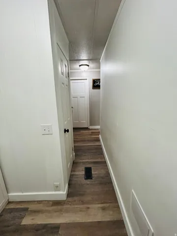 Hallway with wood-finish flooring, white paneling, and a flush-mount ceiling light fixture